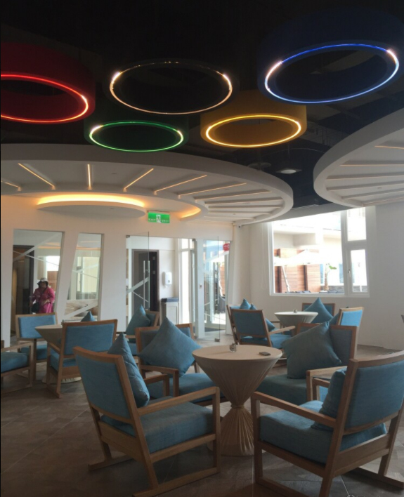 這張「休息室」的照片是一個現代化的休息室,有五個圓形燈,還有藍色的沙發和木頭的桌子。