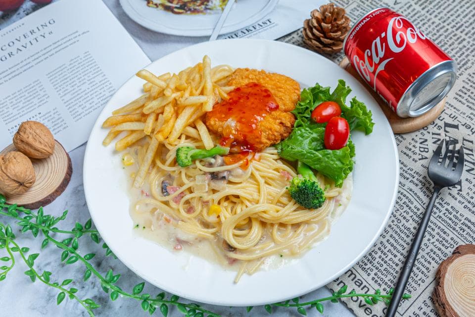 這張「義大利麵」的照片是一盤奶油白醬義大利麵,上面放著炸雞排、薯條和沙拉。