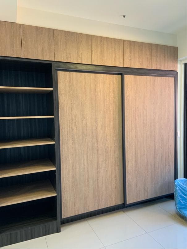 這張照片是一間房間的衣櫃,衣櫃門是木紋色的,而且是滑軌式的。