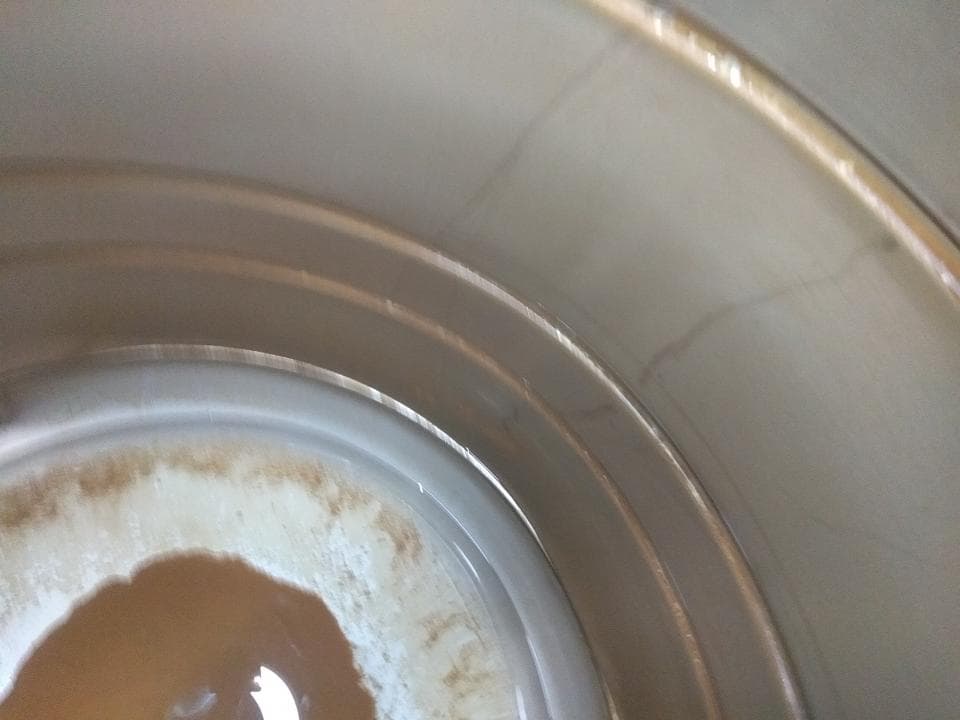 這張照片是一張金屬容器的內部,裡面有一圈深色的污垢。