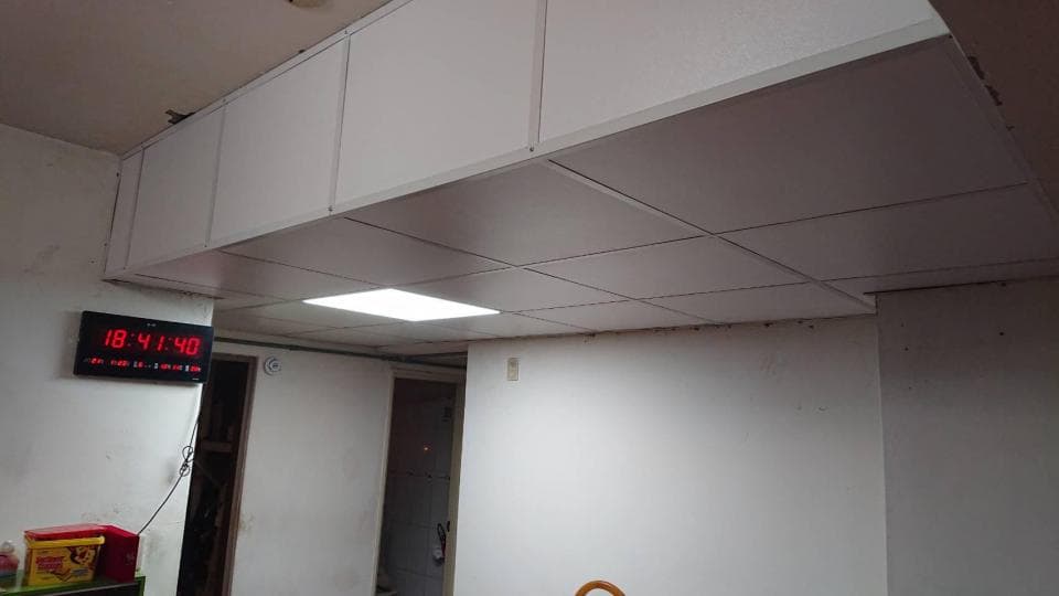 這張照片是一個房間的天花板,天花板是用白色板材做成的,上面裝著白色的方形燈罩,看起來很明亮。