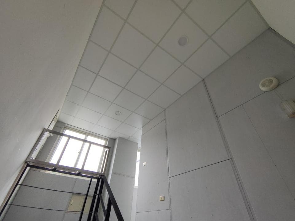 這張照片是一間房間的內部,最顯眼的是房間的天花板,是由多個白色方形的格子拼成的。