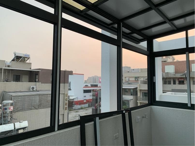 這張照片是一間房間的窗戶,透過窗戶可以看到外面的建築物和天空。