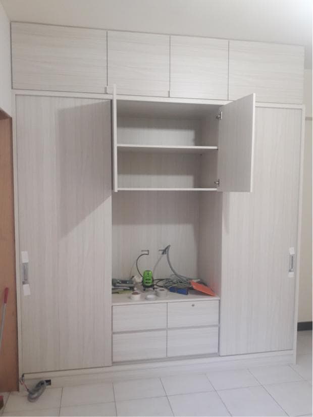 這張照片是一個白色木紋衣櫃,櫃子裡有一個開放式的架子,架子上放著一些物品,櫃子底部有三個抽屜。