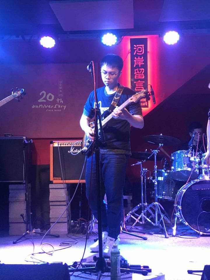 這張照片是一個樂隊在演唱會上表演。照片中最重要的部分是吉他手,他正在演奏一把電吉他,他身穿黑色 T 恤,戴著黑色帽子,他的演奏技術高超,充滿激情,吸引了觀眾的目光。