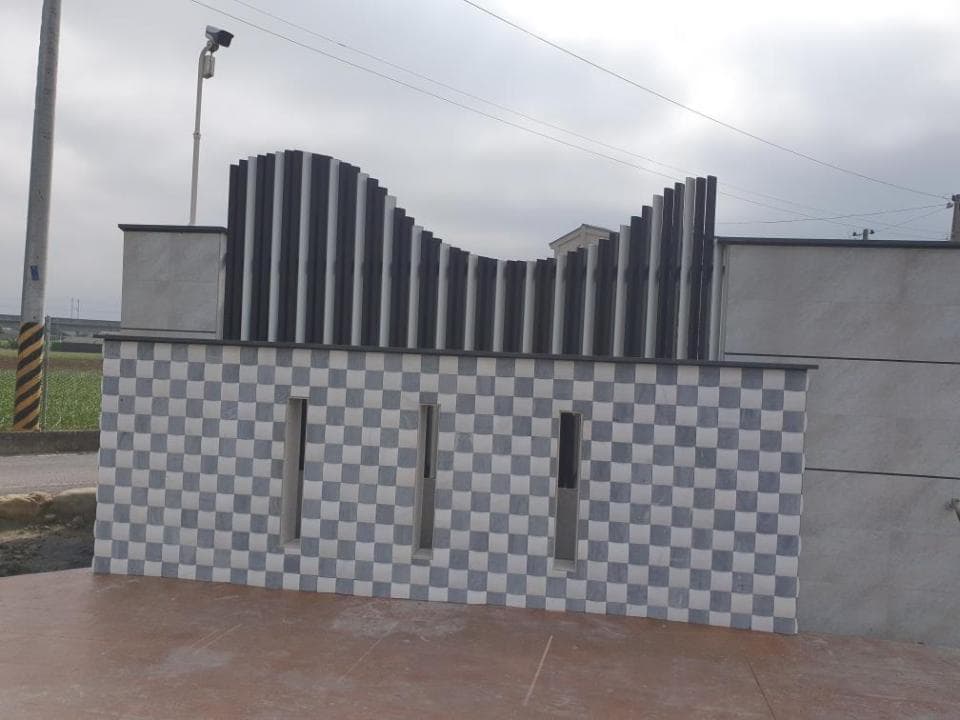 這張「圍牆」的照片是,一個帶有黑色條紋的現代化設計圍牆,牆上裝飾著黑白棋盤格的瓷磚。