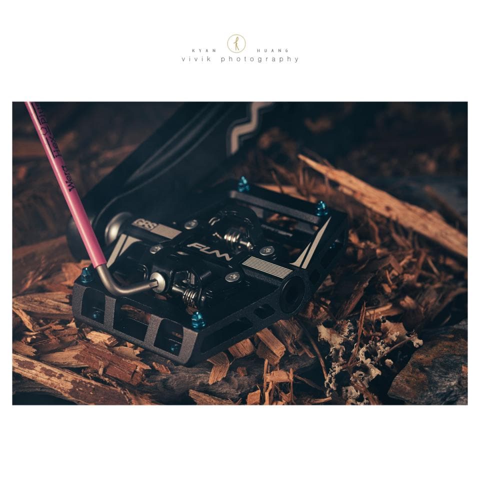 這張「自行車踏板」的照片是黑色的,上面有白色的字樣,旁邊有一把粉紅色的工具。