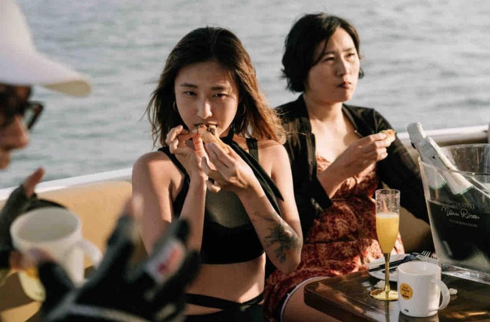 這張「在船上吃東西」的照片是兩個女生,其中一個穿著泳裝,另一個穿著花洋裝,她們在船上吃東西、喝酒聊天。