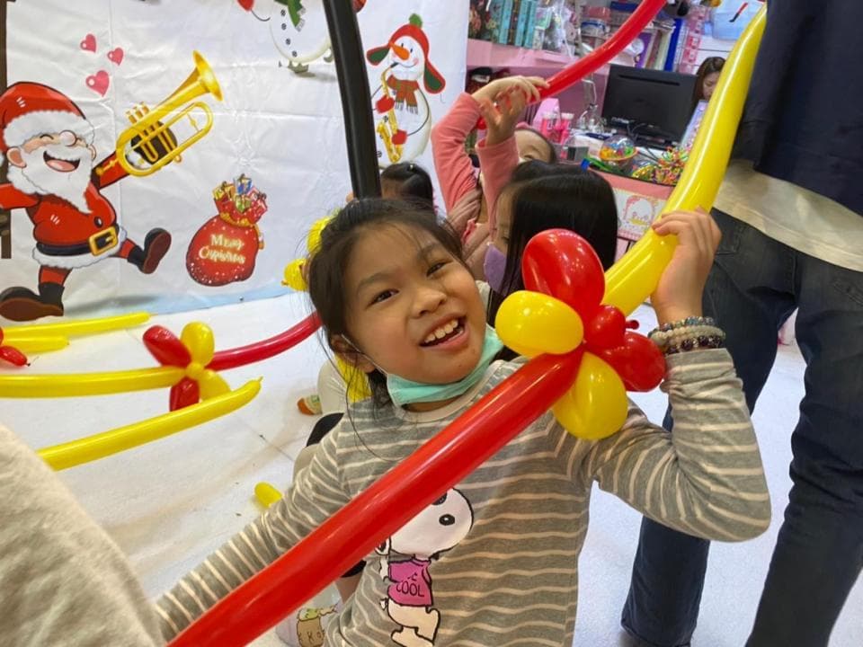 這張照片是一個小女孩拿著氣球,她笑得很開心,這張照片表現出快樂的氛圍。