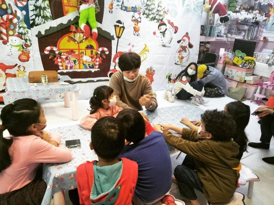 這張照片是一群小朋友圍坐在一張桌子旁,他們戴著口罩,似乎在玩遊戲或學習。