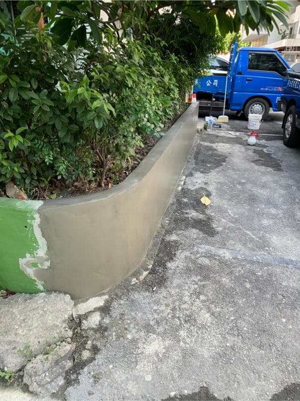 1) 照片顯示一個水泥路緣石,上面有一層綠色的油漆