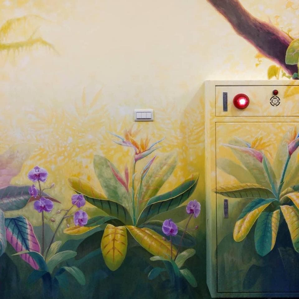 這張「牆壁」的照片是一面黃色的牆壁,上面畫著一些花朵和樹葉,牆壁上還有一個紅色的警示燈。
