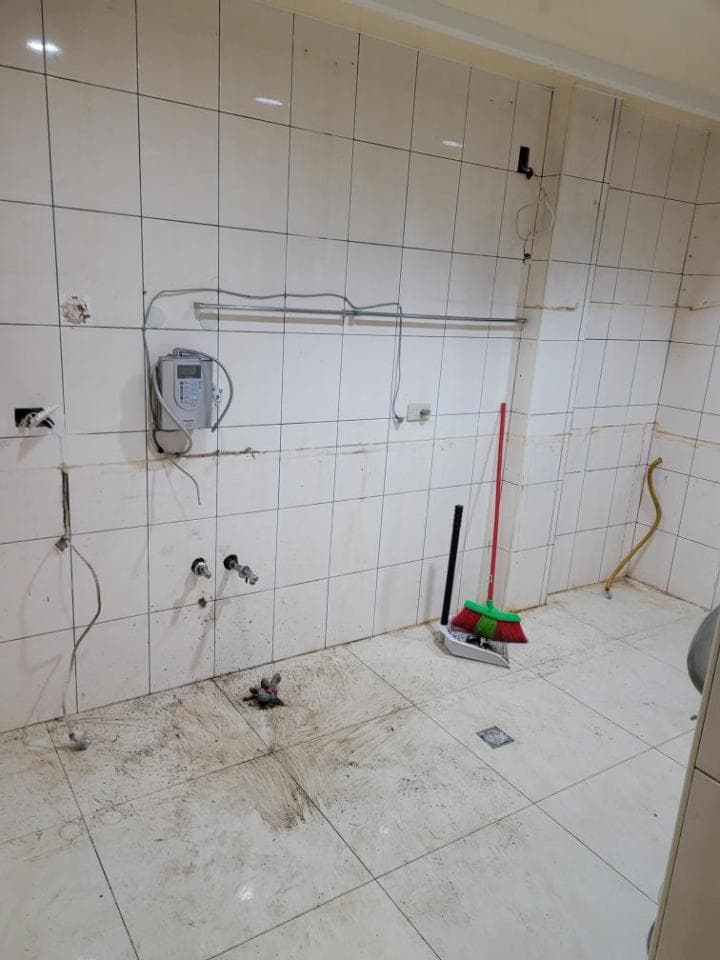 這張照片是一間正在裝修的浴室,浴室裡面的牆壁已經貼上了白色的磁磚,地板也鋪設完成了,但是還沒完全清潔乾淨。