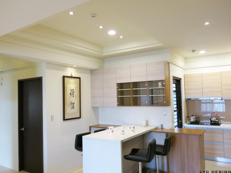 這張照片是一間現代化的廚房,裡面有一個玻璃櫃和一個木製的餐桌。玻璃櫃裡有許多物品,餐桌上有幾杯水和一些盤子。