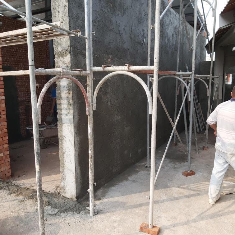 1) 照片顯示一間正在施工中的房屋,房屋外牆已經完成粉刷,一旁設有鷹架,地上有水泥沙漿