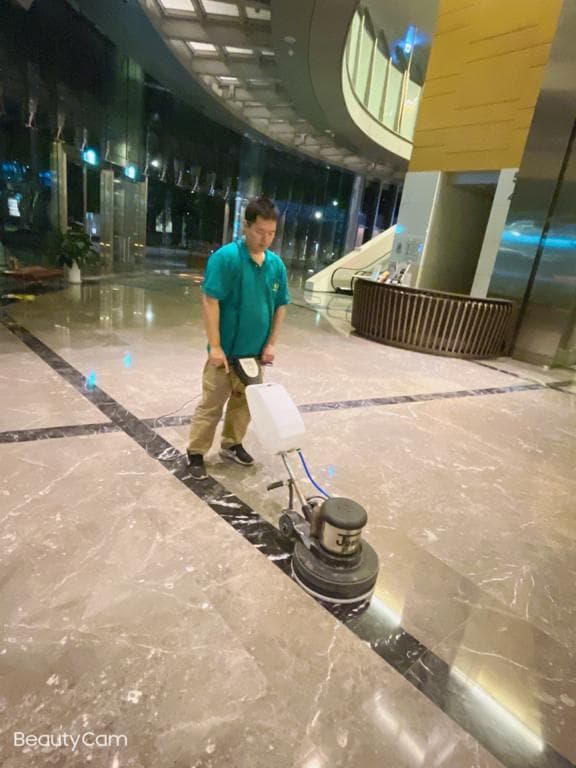1) 照片顯示一位男子在大型建築物的大理石地板上使用磨光機清潔地板