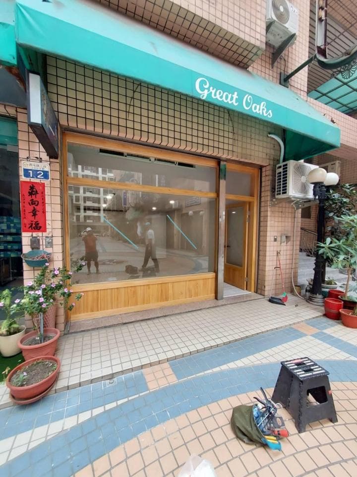 這張「Great Oaks」商店的照片是一家正在裝修的店面,店面有綠色的遮陽棚,以及木質的門窗。