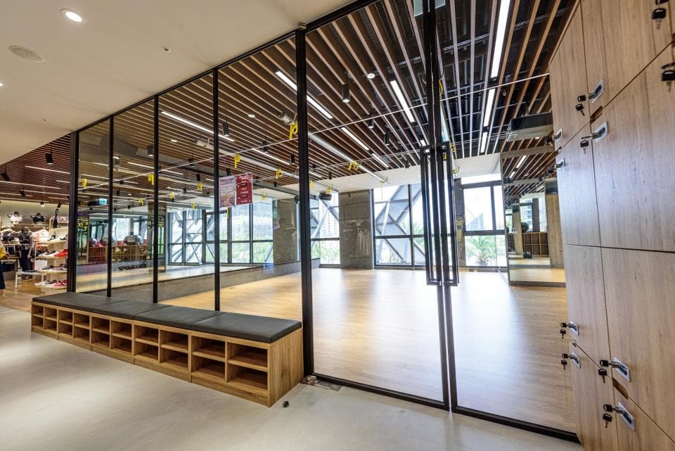 這張「健身房」的照片是一個現代化的健身房,有著木質的裝飾,牆上是木製的儲物櫃,房內還有一個鏡面牆,方便人們運動時觀察自己的動作。