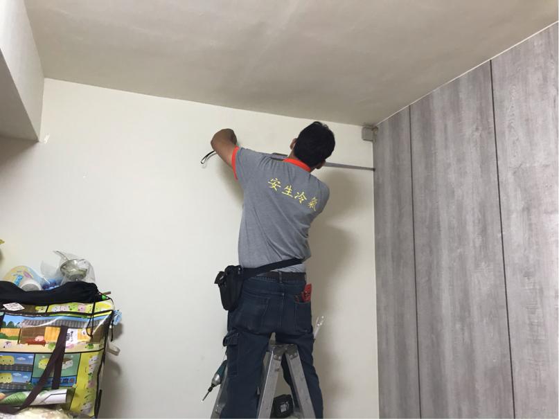 一名身穿灰色 T 恤的男性正在使用工具安裝木板