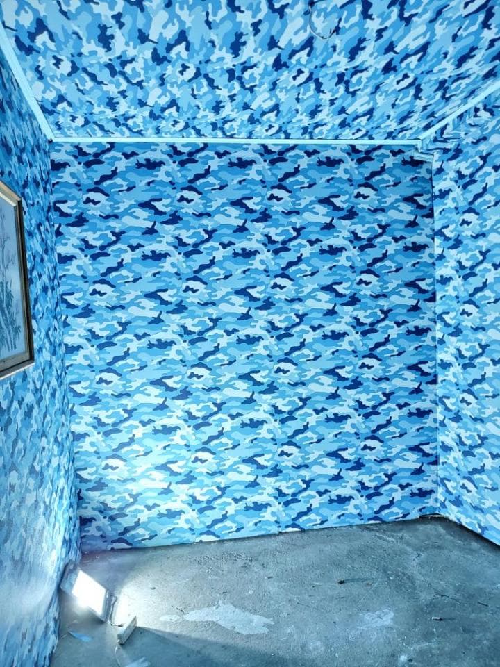 這張照片是一個藍色迷彩圖案的房間。房間的牆壁和天花板都覆蓋著這種圖案,營造出令人驚嘆的視覺效果。