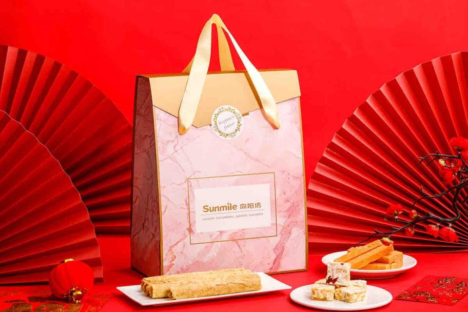 這張「禮物盒」的照片是一個裝飾著紅色和金色紙扇的粉紅色禮盒。