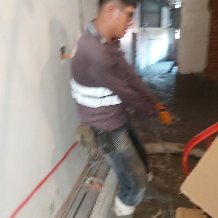 1) 照片中顯示一位身穿棕色上衣、白色背心和藍色牛仔褲的男性