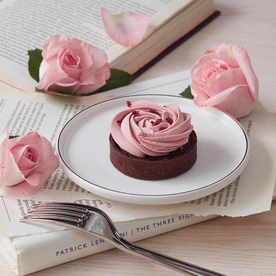這張「甜點」的照片是一塊覆蓋著粉紅色奶油的巧克力蛋糕,旁邊放著一些粉紅色的玫瑰花。