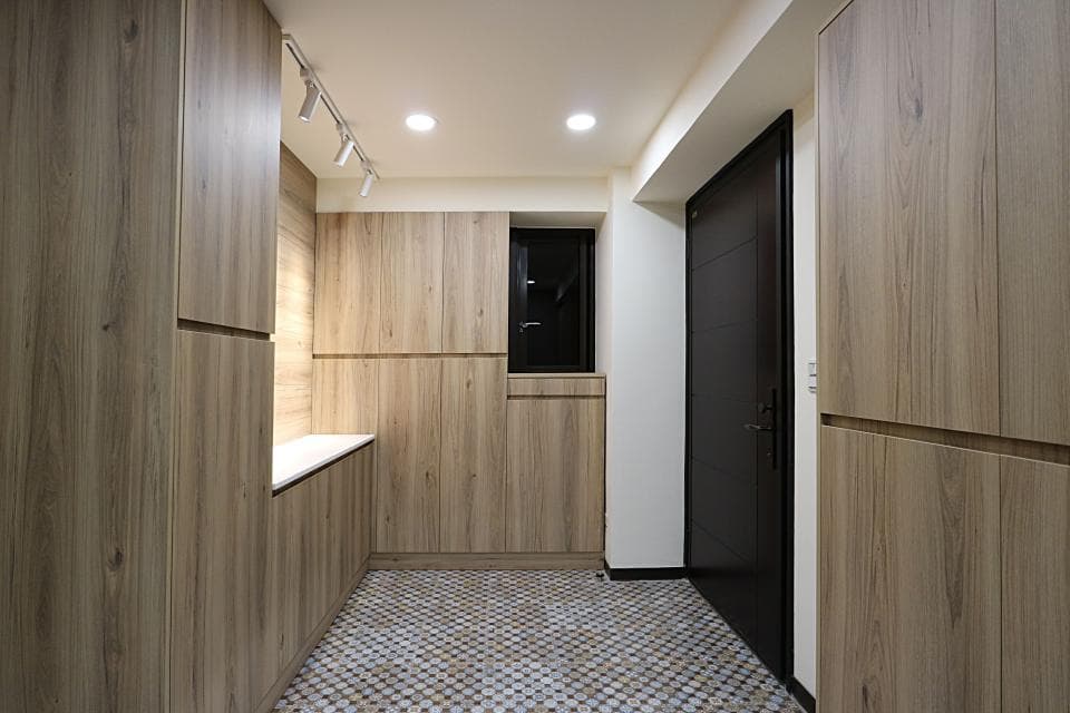 這張照片是一個簡約現代的室內設計,主要以木質色調為主,牆壁和櫃子都採用了木紋板材,並搭配了白色磁磚地板,營造出溫馨舒適的空間氛圍。