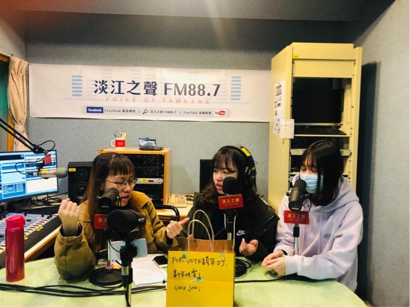 這張「電臺錄音」的照片是三名女生正在錄製節目,背景有電臺的標誌,還有收音設備。