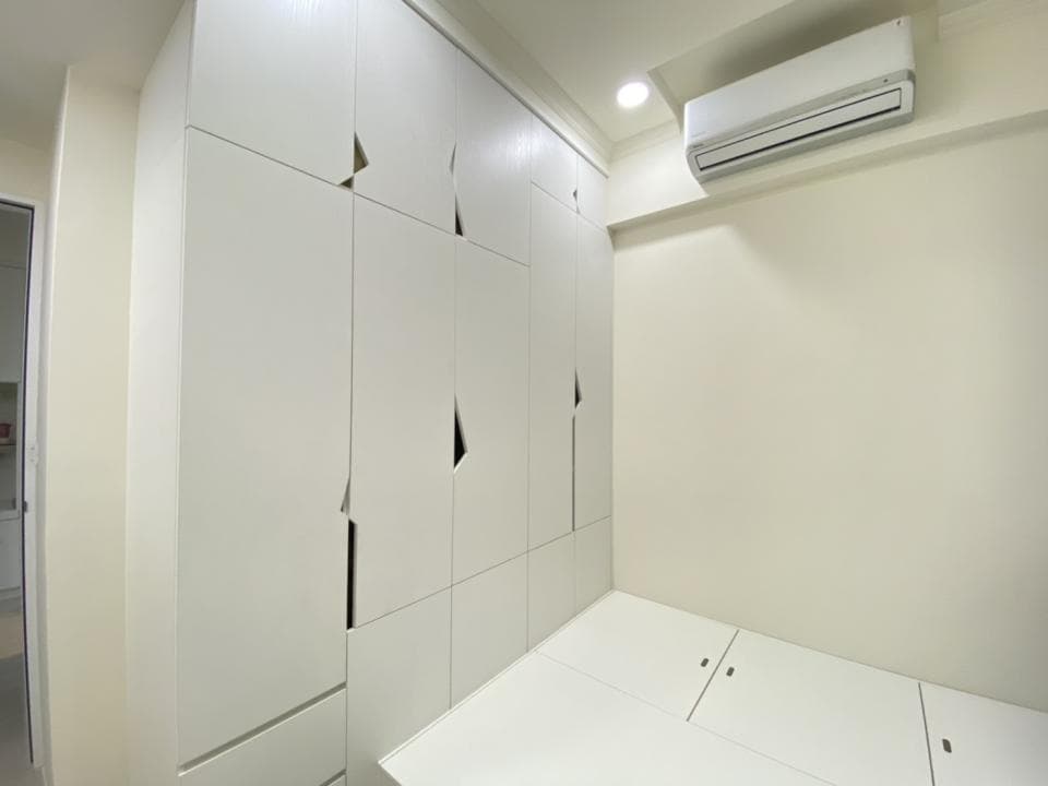 這張照片是一個現代化的臥室,最顯眼的是房間左側的白色衣櫃,它是由多個櫃子組成,設計獨特,看起來非常簡潔,整潔,令人感到舒適。