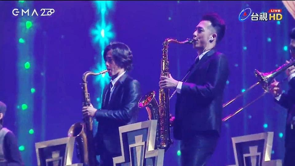 這張「樂隊演奏」的照片是兩位穿著黑色西裝的音樂家正在吹奏薩克斯風。