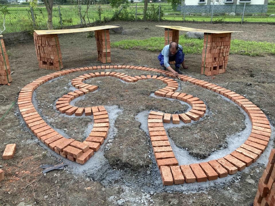 1) 照片顯示一個由紅磚鋪成的迷宮,迷宮中間有一個男人