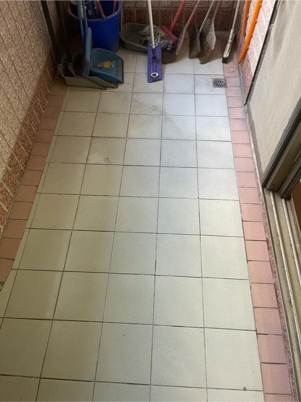 1) 照片顯示一個乾淨的瓷磚地板,右側有一排紅色的磚塊,左側有一部分牆壁,靠近照片邊緣有一扇門