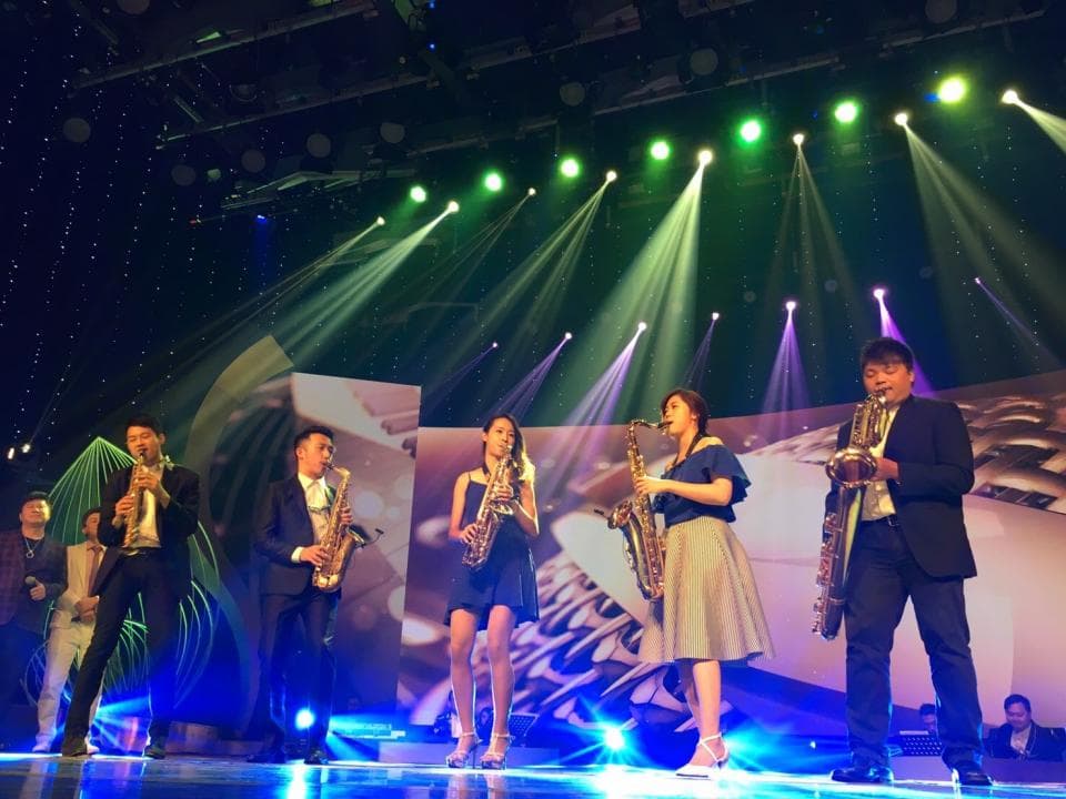 這張「薩克斯風演奏」的照片是四位音樂家在舞臺上演奏,他們穿著正式的服裝,背景是亮麗的舞臺燈光。