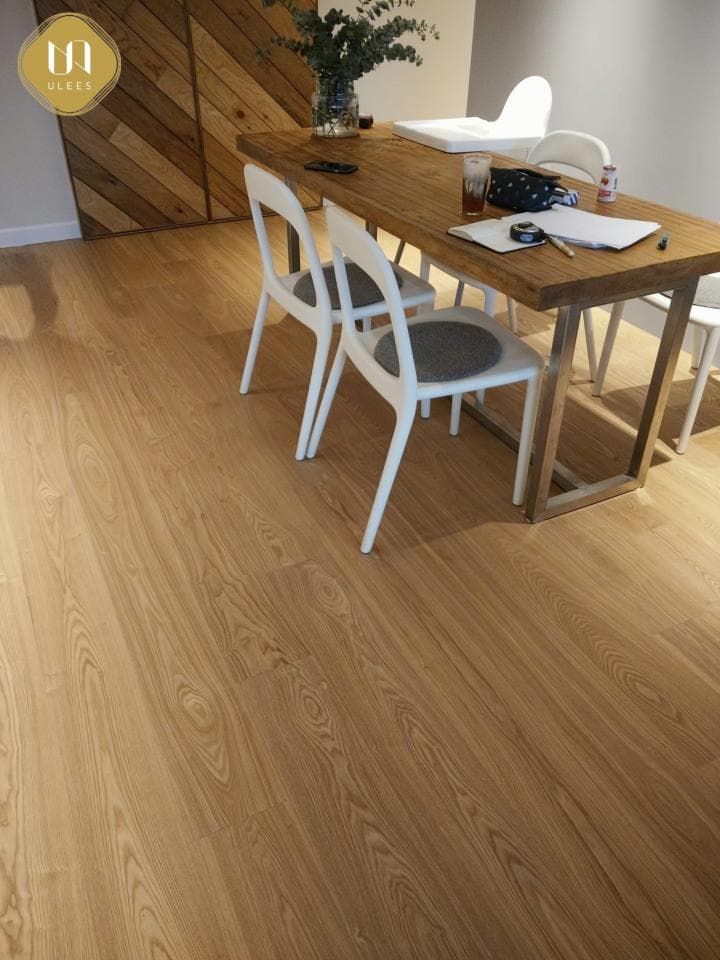 1) 照片顯示一個帶有木質地板的房間,房間裡有木桌和白色椅子