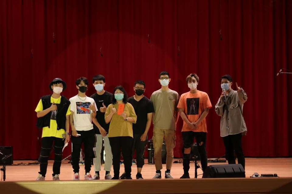 這張「七位戴著口罩的年輕人站在舞臺上」的照片是,他們看起來像是樂團成員,正在表演或是參加比賽。