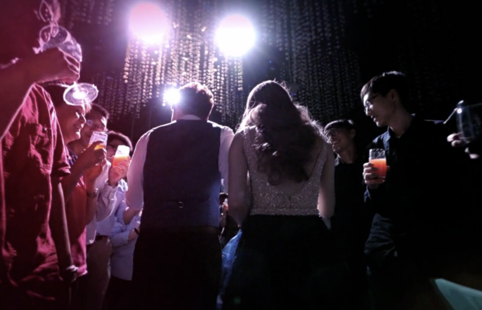 這張照片是一群人在一個昏暗的房間裡聚會,他們看起來很開心,而且正在舉杯慶祝。