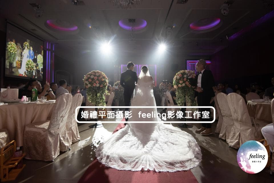 這張照片是一對新人正在步入禮堂,新娘穿著優雅的婚紗,新郎則穿著西裝,他們身後是滿滿的祝福與歡笑。