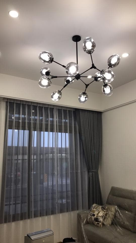 1) 照片顯示一個現代客廳,天花板裝飾著一個黑鐵骨架、玻璃燈罩的吊燈