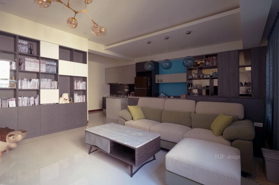 這張「客廳」的照片是一個現代化的空間,裡頭擺放了大型的沙發和一個簡潔的茶几,旁邊有一個大型的書櫃,牆上裝飾著許多燈光。