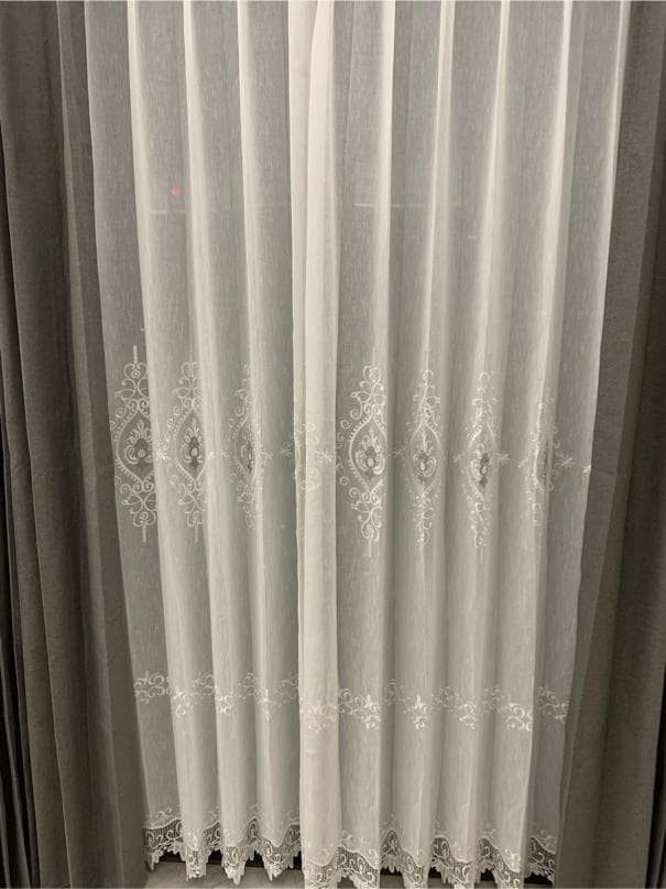 1) 照片顯示了一對白色蕾絲窗簾,窗簾上有精緻的花卉圖案,底部有蕾絲邊緣