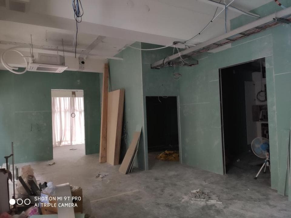 1) 照片顯示一個正在裝修的房間,房間內部牆壁都已完成粉刷,但地坪尚未完成,還有許多施工器材