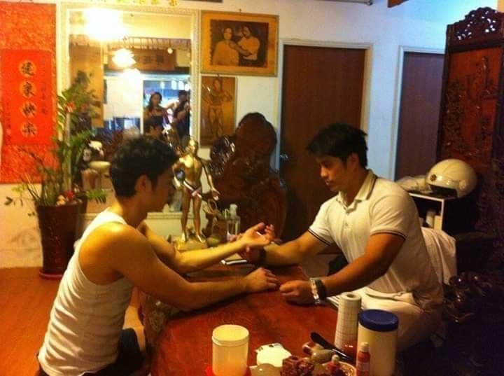 這張照片是兩個男人在一個木製的桌子上,其中一個男人正在用手觸摸另一個男人的手。