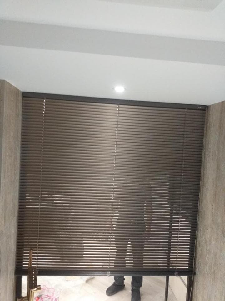 1) 照片顯示一個房間裡裝有棕色百葉窗的窗戶,窗戶下有兩個模糊的人影