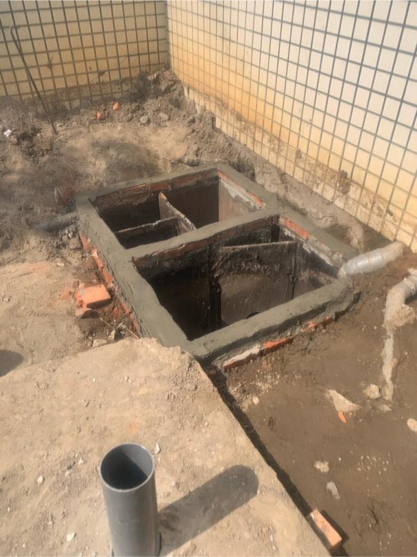 這張照片是一個正在施工中的化糞池,化糞池由水泥砌成,分為三個隔間,每個隔間都有一個開口,方便清理和維護。