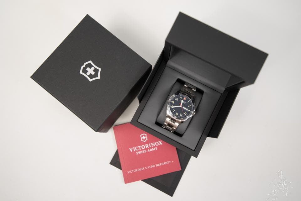 這張照片是一隻維氏手錶放在黑色的盒子裡。手錶是銀色的,錶盤是黑色的,有紅色數字和指針。盒子打開,露出手錶,旁邊有一張紅色的保證書。
