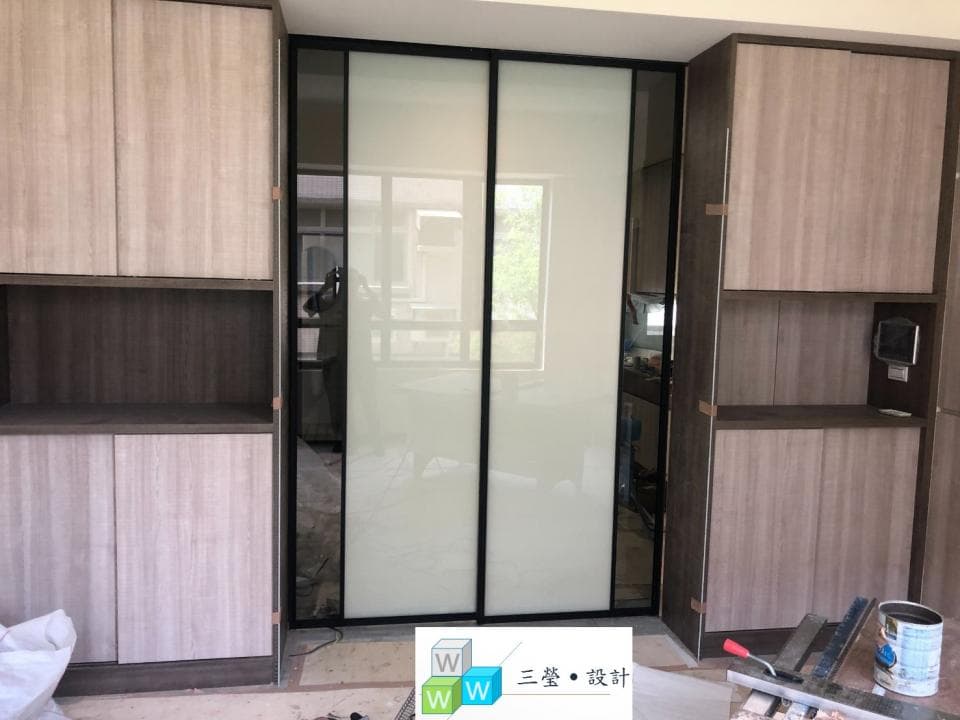 這張照片是一間現代化的浴室,最重要的部分是中間的黑框玻璃門,它將浴室分為兩部分,一邊是淋浴區,另一邊是洗漱區。