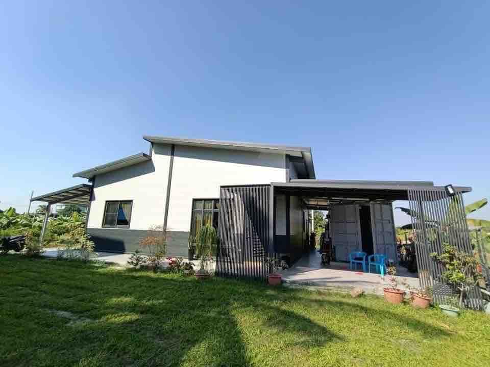 1) 照片顯示一棟白色的現代建築,外觀為簡約設計,有黑色金屬欄杆,屋頂為斜屋頂,屋前有草坪和綠色植物