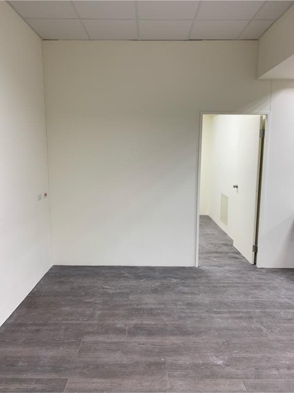 這是一張空房間的照片,房間裡有灰色的地板、白色的牆壁和天花板