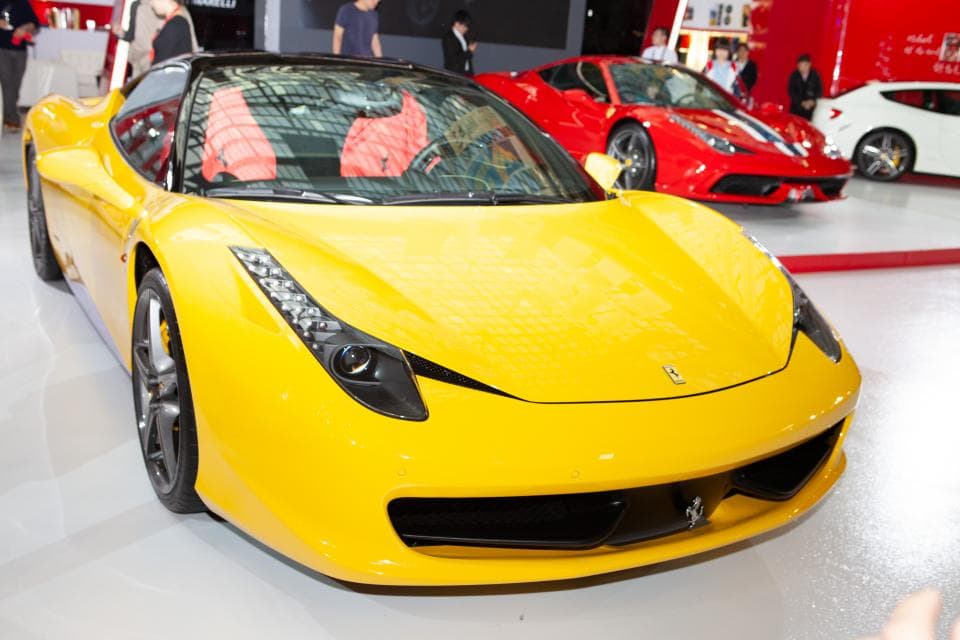 這張「法拉利」的照片是一輛黃色的跑車,它停在展廳裡,旁邊還有一輛紅色的跑車。